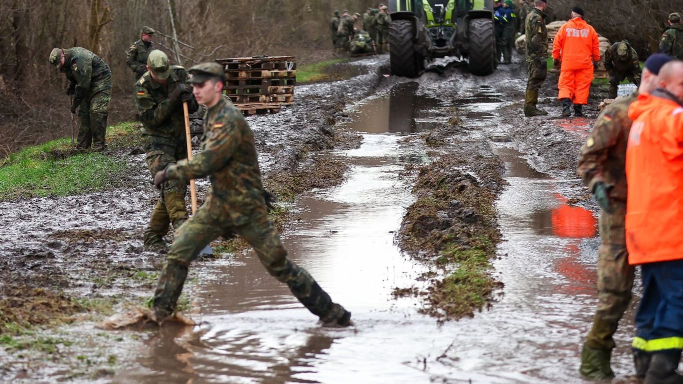 Oberröblingen: Soldatinnen und Soldaten der Bundeswehr sichern einen Deich an der Helme mit Sandsäcken.