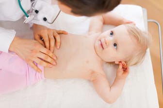 Eine Ärztin tastet den Bauch eines Kleinkinds ab