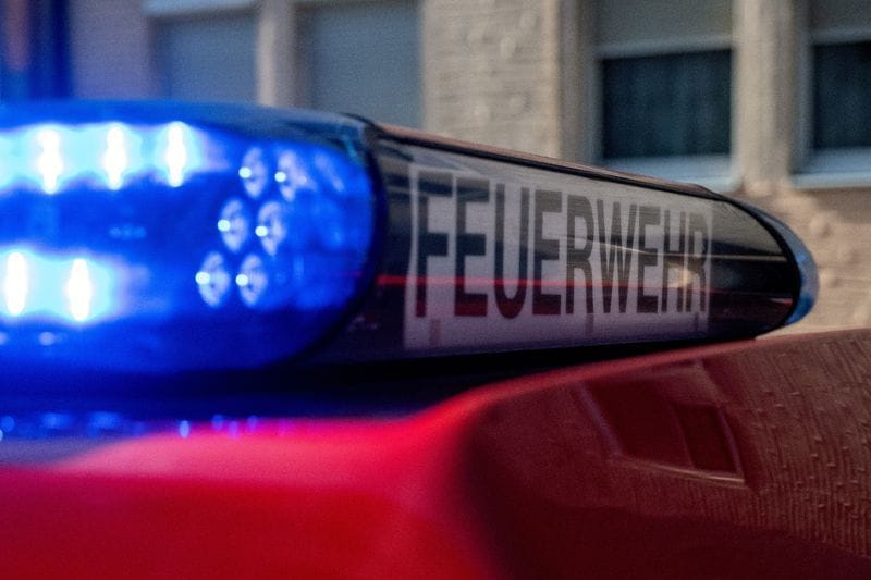 Ein Fahrzeug der Feuerwehr steht mit eingeschaltetem Blaulicht an einem Einsatzort.