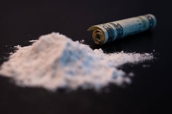 Kokain neben einem gerollten Geldschein (Symbolbild): Bei einer Drogenrazzia in Belgien haben Polizisten drei Kollegen festgenommen.