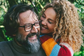 Mann und Frau mittleren Alters lachend in freundschaftlicher Umarmung