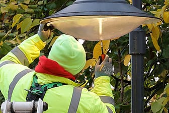 Ein Techniker installiert eine Straßenlampe (Symbolbild): In Erlangen wird nun ein besonderes Modell getestet – ob es bei den Bürgern ankommt?