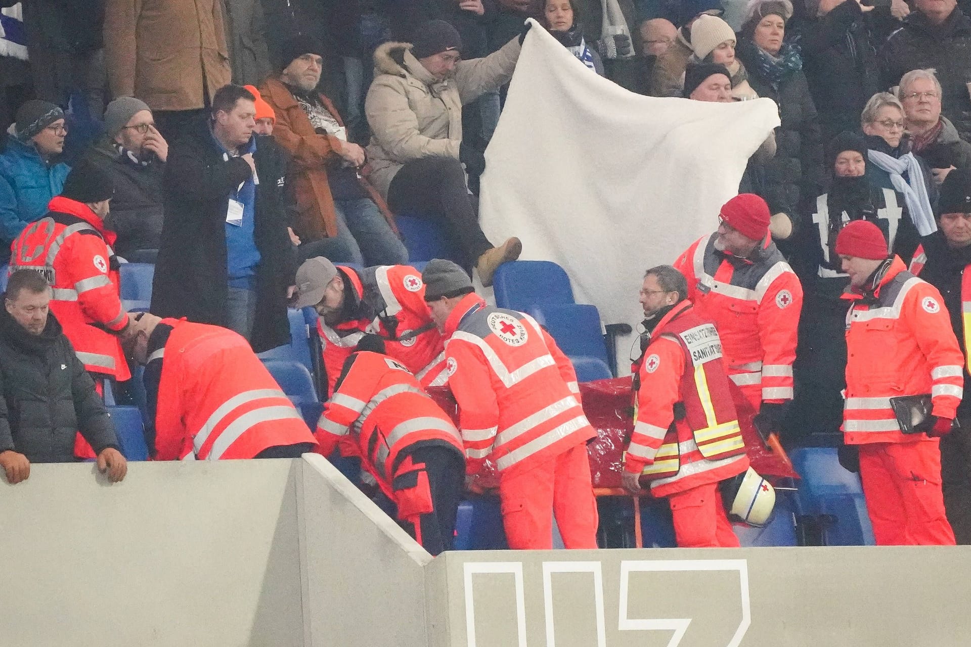 Bange Momente: Sanitäter auf der Tribüne in Darmstadt, Fans halten einen Sichtschutz hoch.