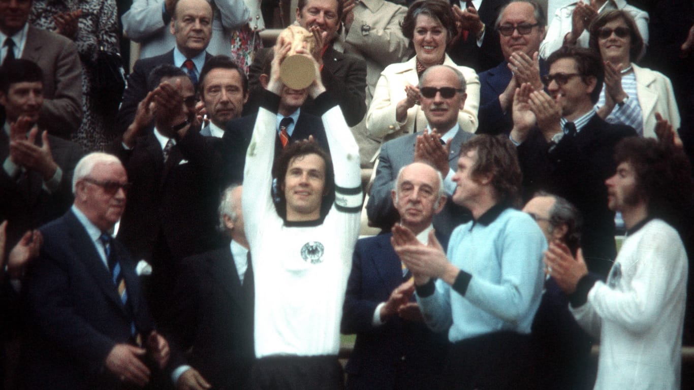Kapitän Franz Beckenbauer reckt den WM-Pokal in die Höhe. Neben ihm (v.l.) seine Teamkollegen Sepp Maier und Paul Breitner.