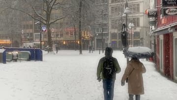 Auch der Rathausplatz ist mit Schnee bedeckt. Manch ein Spaziergänger hat sicherheitshalber einen Regenschirm dabei.