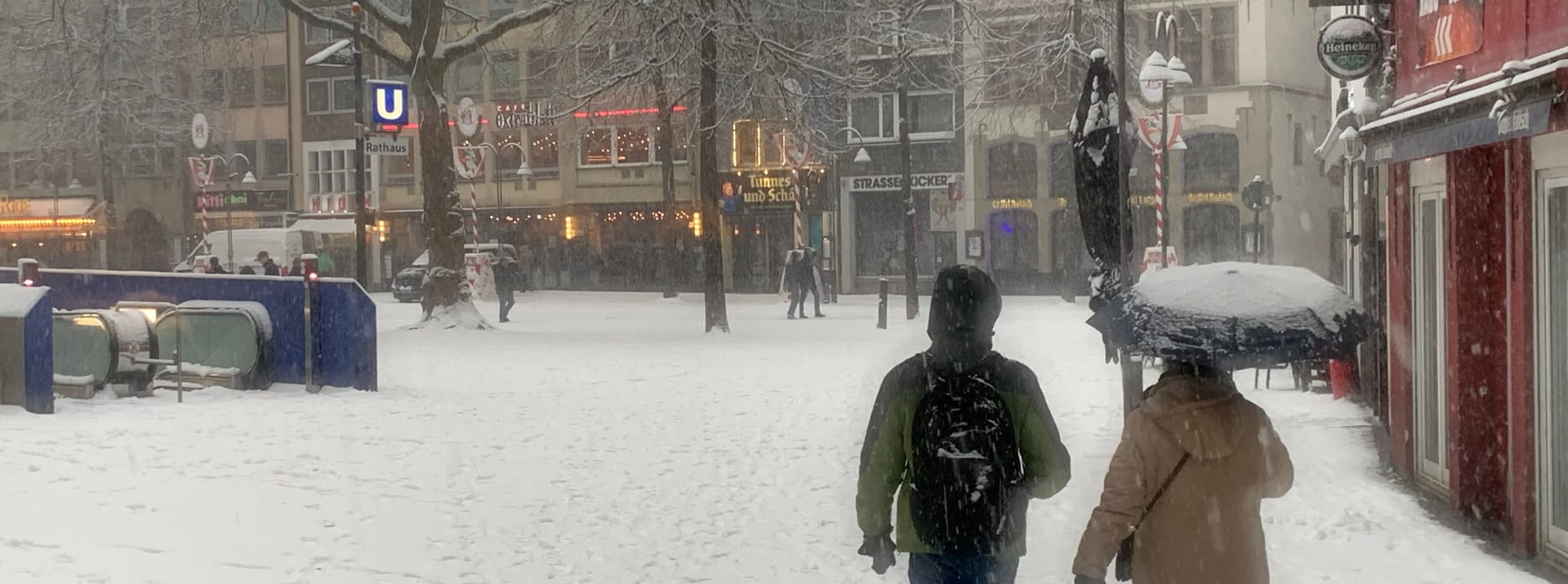 Auch der Rathausplatz ist mit Schnee bedeckt. Manch ein Spaziergänger hat sicherheitshalber einen Regenschirm dabei.