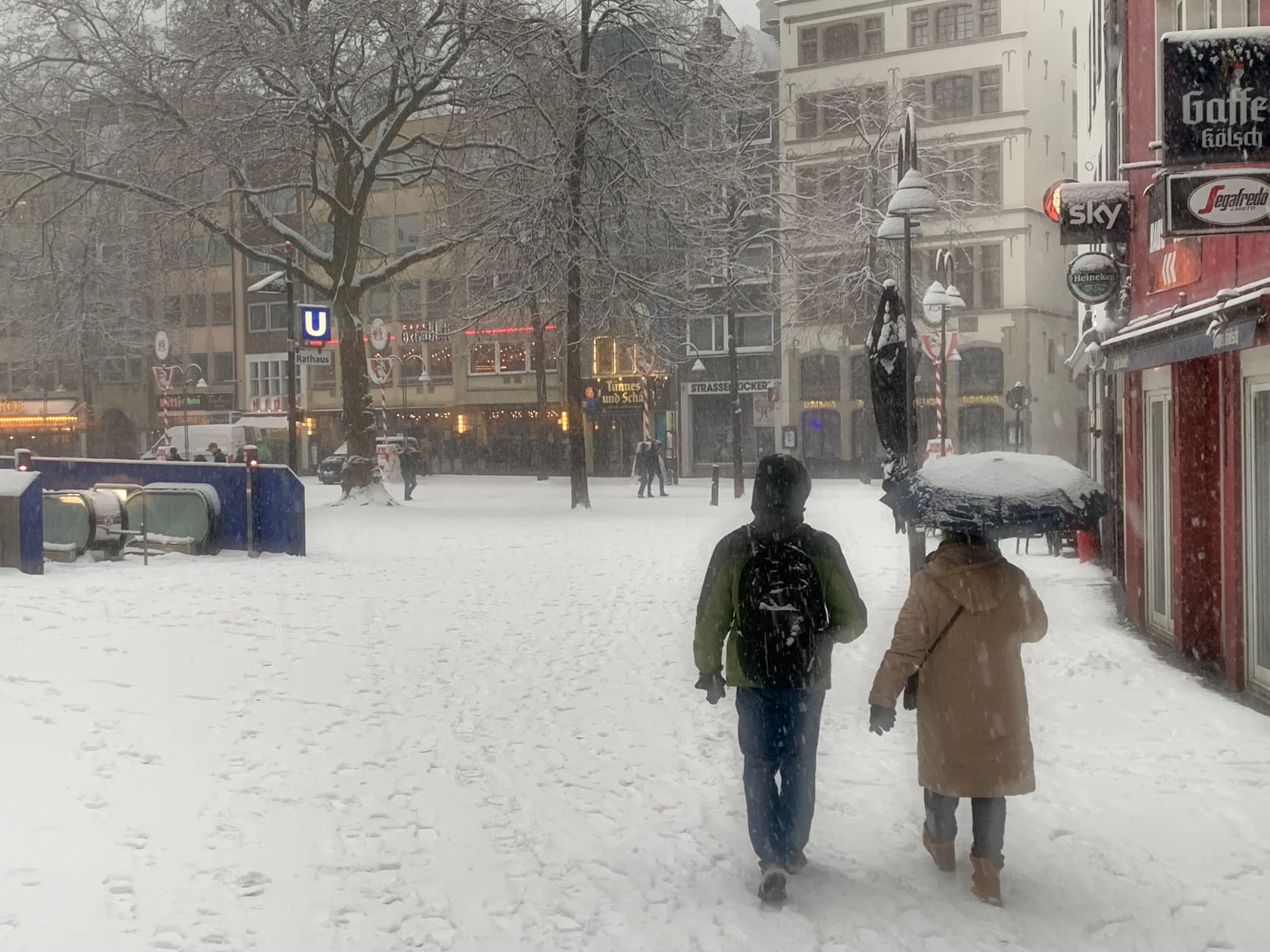 Auch der Rathausplatz ist mit Schnee bedeckt. Manch ein Spaziergänger hat sicherheitshalber einen Regenschirm dabei.