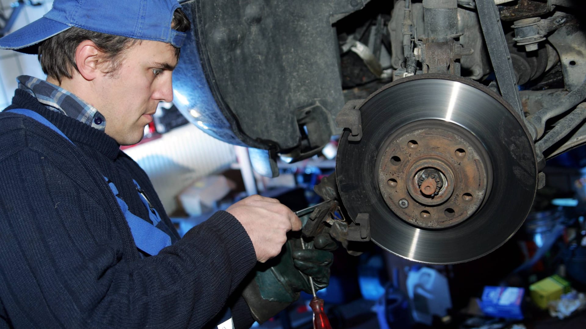 Ein Kfz-Mechaniker erneuert die Bremsbeläge an einem Pkw.