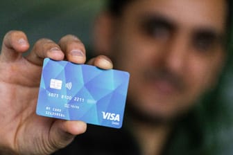 Ein Flüchtling hält eine Bezahlkarte in der Hand: Zusammen mit Sozialkürzungen für Asylbewerber sollen die Karten dafür sorgen, dass Deutschland unattraktiver für Flüchtlinge wird.
