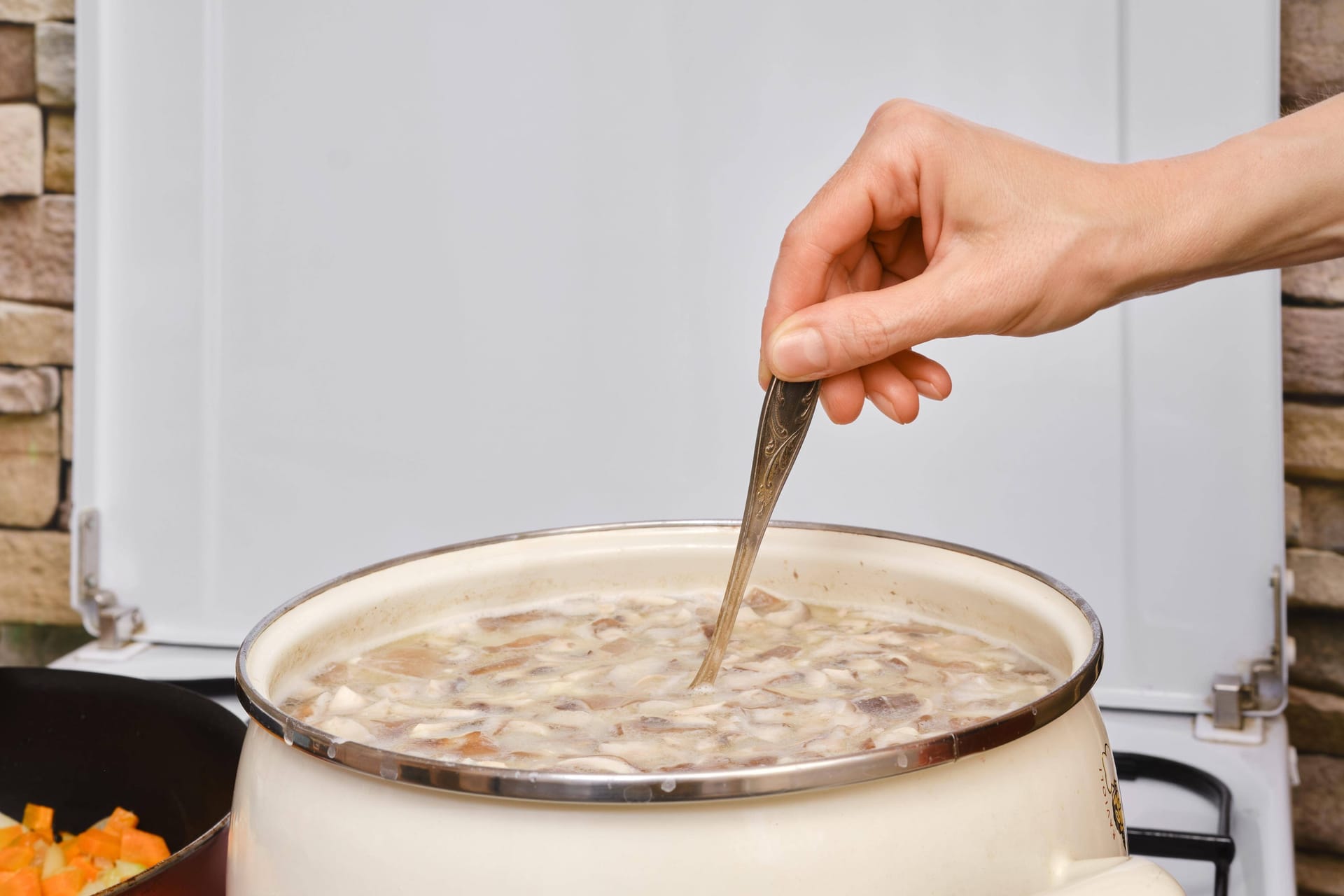 Frau rührt Suppe in einer Kasserolle auf dem Herd (Symbolfoto): Der 1. FCN verteilt am 29. Januar Schäufele-Suppe im ClubHaus.