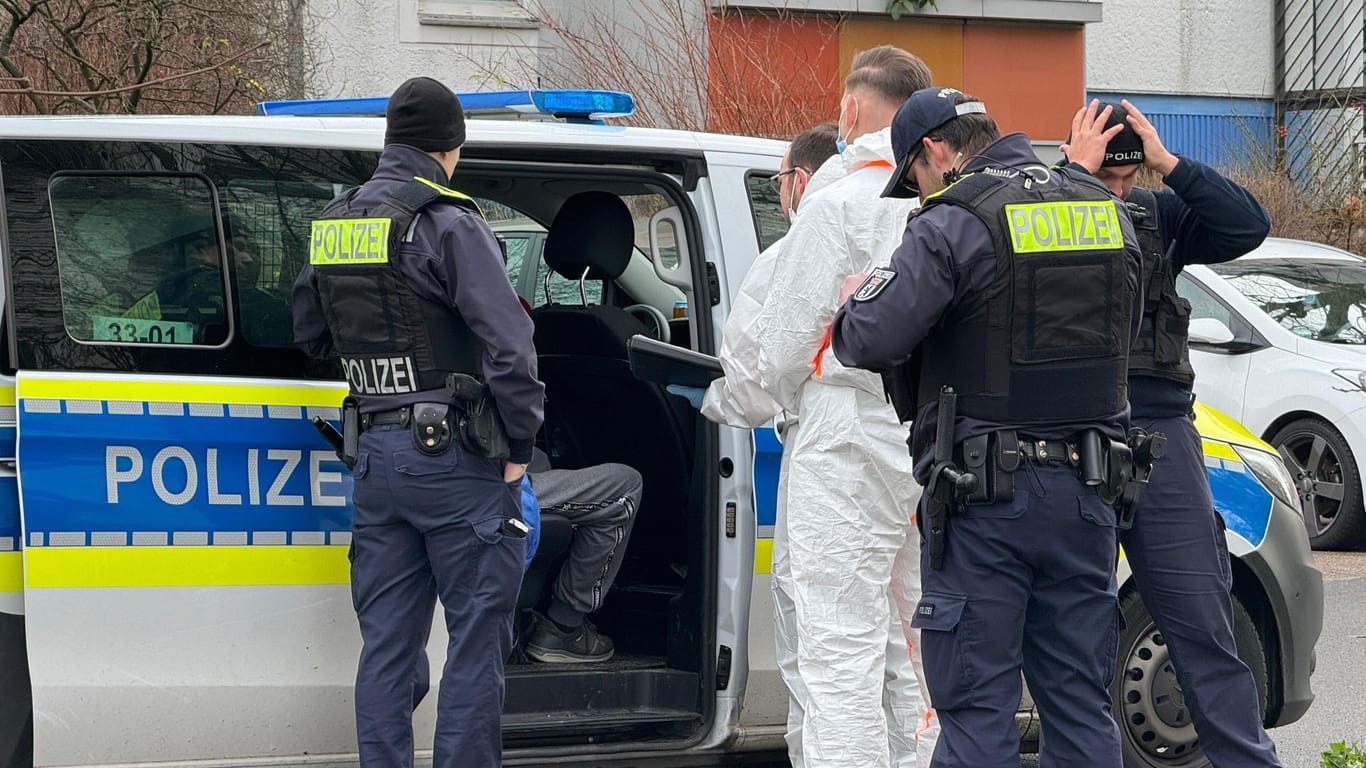 Polizeibeamte sprechen mit einem Mann der in einem Polizeifahrzeug sitzt: Ein 71-jähriger Mann ist nach dem gewaltsamen Tod seiner Ehefrau in Berlin-Hellersdorf festgenommen worden.