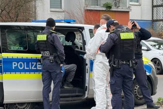 Polizeibeamte sprechen mit einem Mann der in einem Polizeifahrzeug sitzt: Ein 71-jähriger Mann ist nach dem gewaltsamen Tod seiner Ehefrau in Berlin-Hellersdorf festgenommen worden.