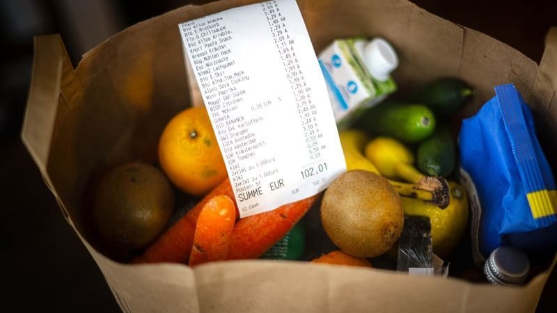 Ein Kassenbon liegt auf den Lebensmitteln in einer Einkaufstüte (Symbolbild): Die Inflation in NRW ist gestiegen.