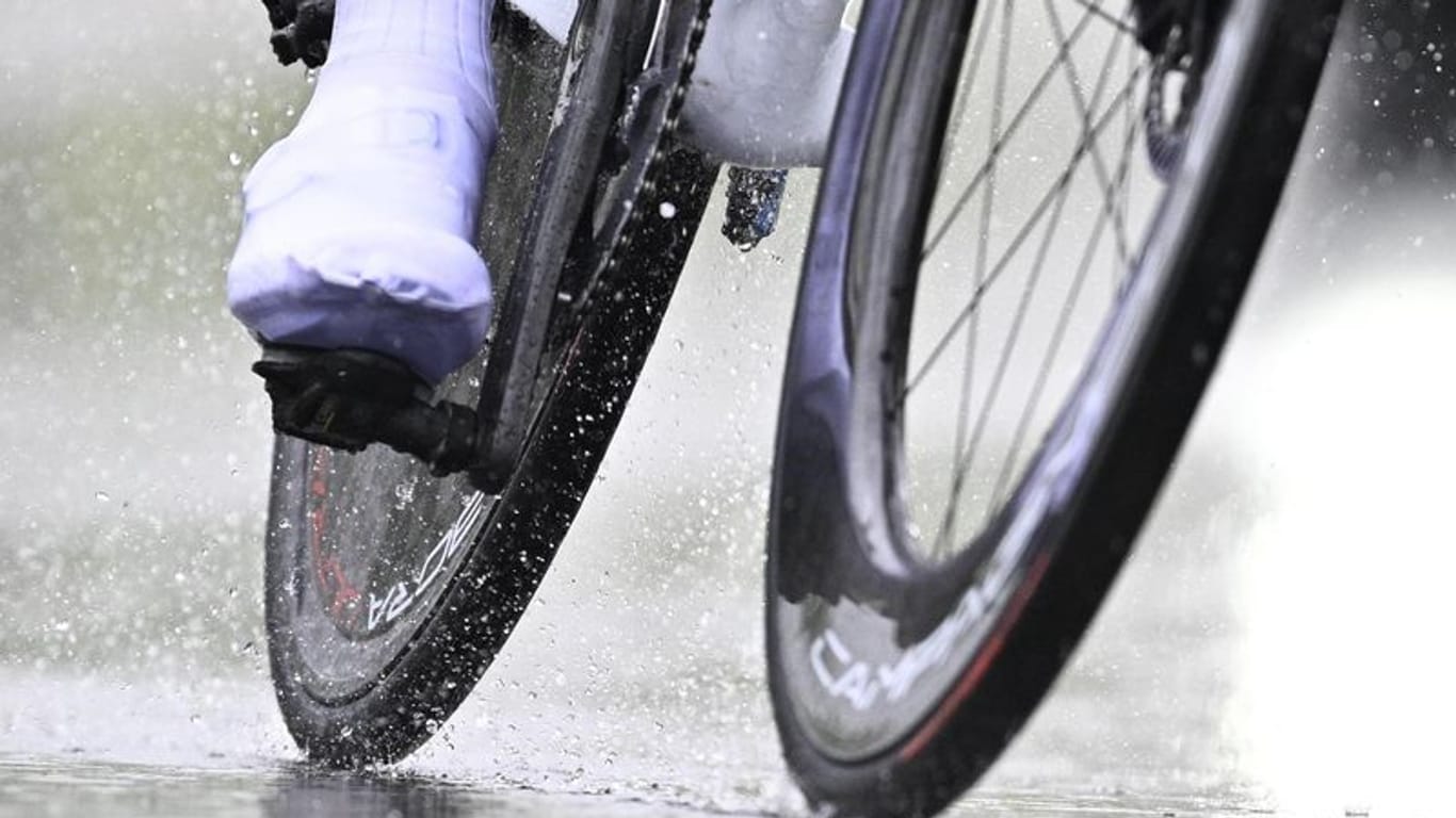 Ein Radfahrer fährt bei Regen über eine Straße (Symbolbild): Am Wochenende soll der Dauerregen nachlassen.