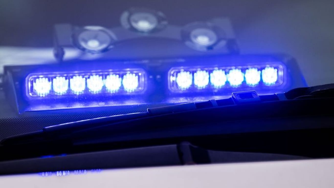 Ein Blaulicht leuchtet unter der Frontscheibe eines Einsatzfahrzeugs der Polizei.