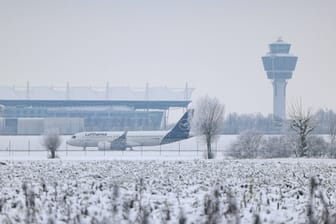 Eine Maschine der Lufthansa steht am verschneiten Münchner Flughafen (Archivbild).