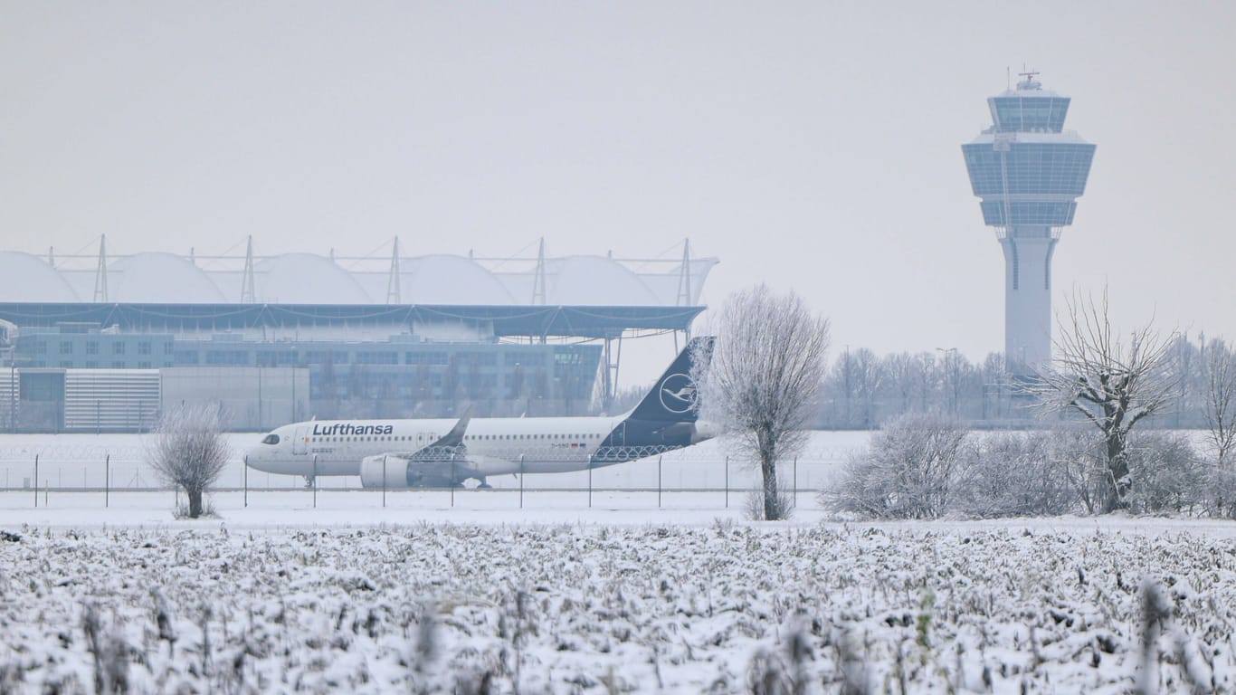 Eine Maschine der Lufthansa steht am verschneiten Münchner Flughafen (Archivbild).
