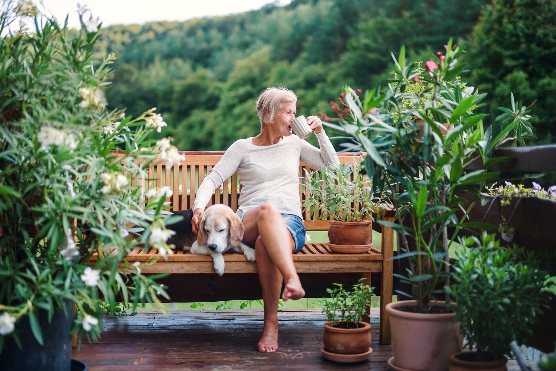 Frau sitzt auf ihrer Terrasse und trinkt Kaffee