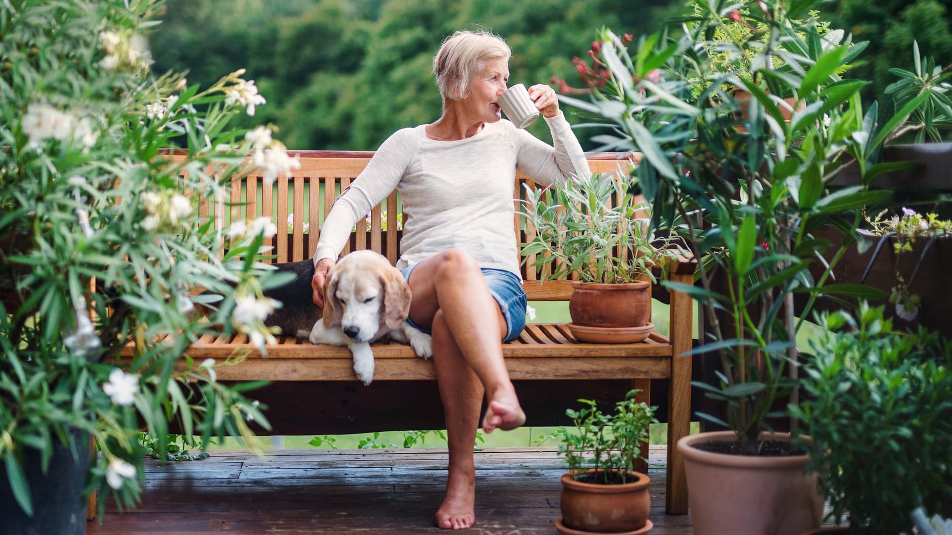 Frau sitzt auf ihrer Terrasse und trinkt Kaffee