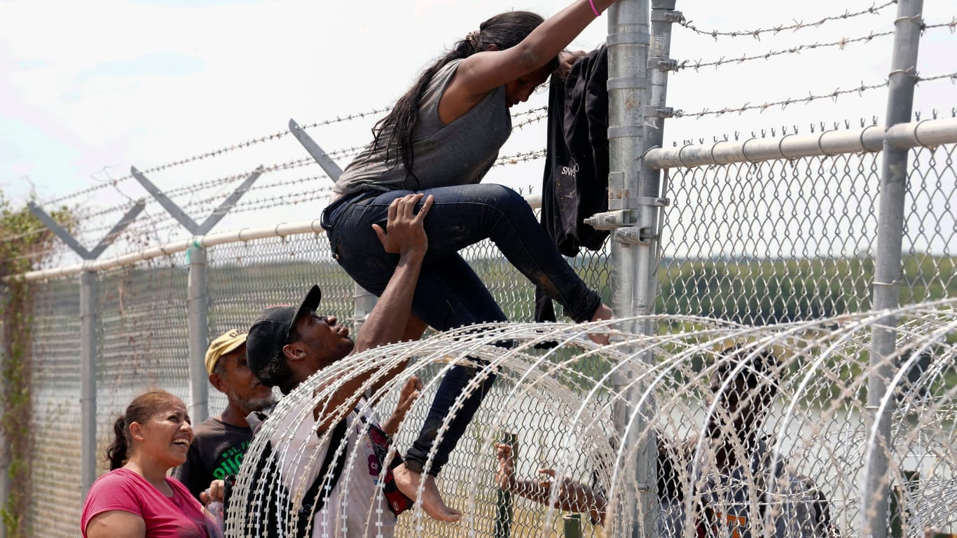 Migranten übersteigen den Grenzzaun in der USA: Der texanische Gouverneur fordert, die Grenze der Vereinigten Staaten mit drastischeren Mitteln zu schützen.