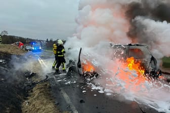 Einsatzkräfte der Feuerwehr löschen brennende Fahrzeuge: Nach einem Unfall im Saarland hatten sie Feuer gefangen.