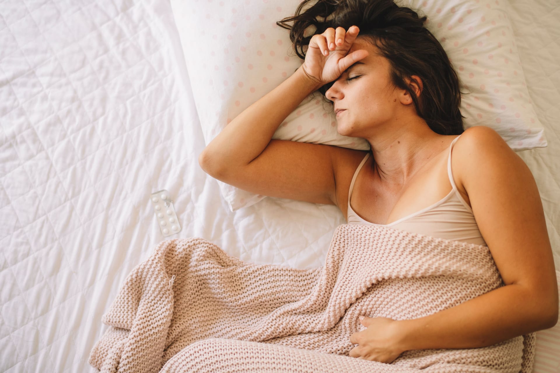 Frau liegt mit Bauchweh im Bett