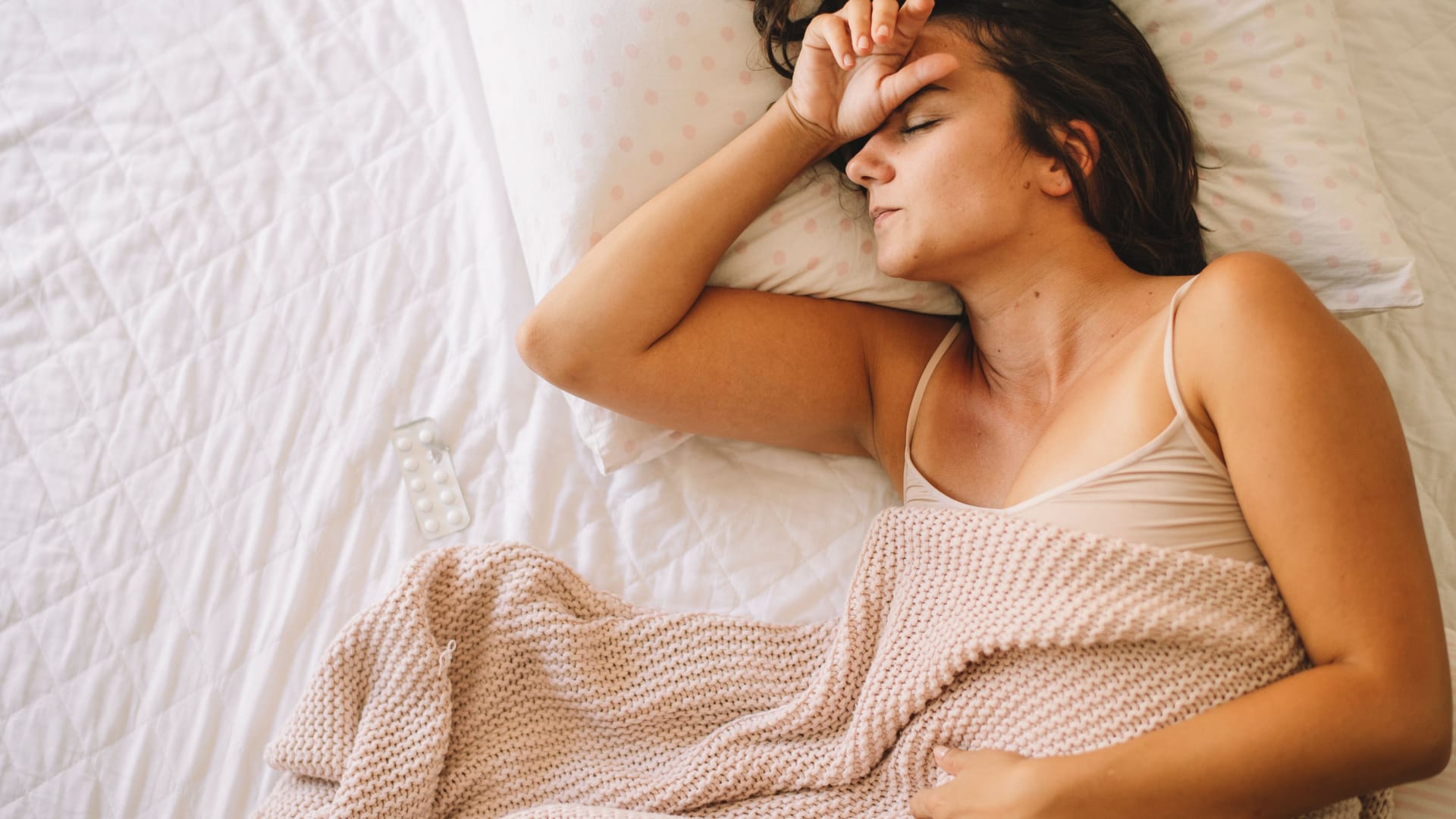 Frau liegt mit Bauchweh im Bett