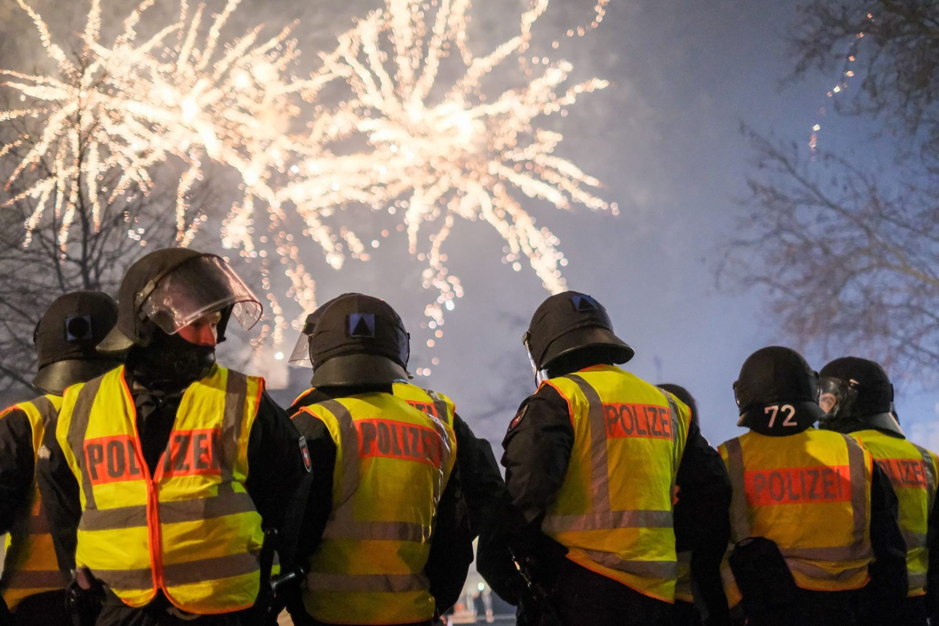 Polizeibeamte stehen vor einem Feuerwerk: Die Zahl der Straftaten gegenüber Einsatzkräften in der Silvesternacht ist noch unbekannt.