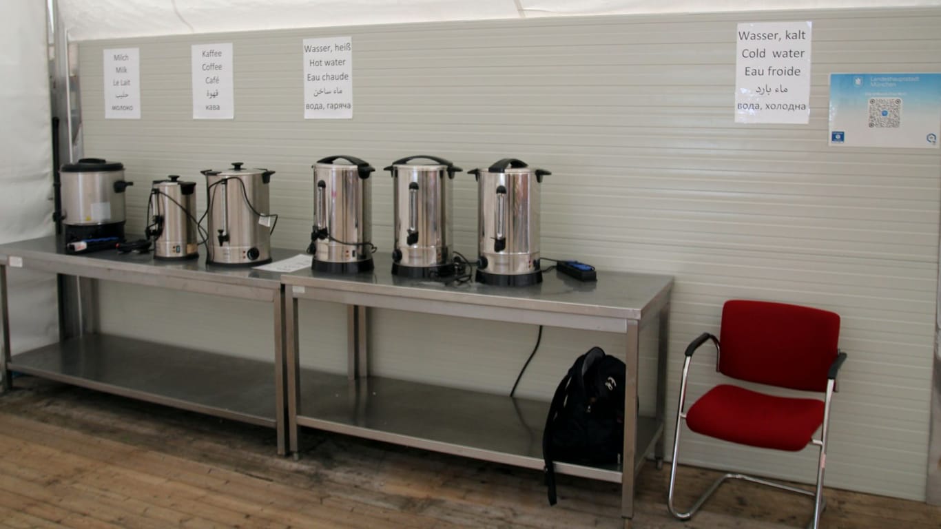 Behälter für Wasser, Kaffee und Milch stehen bereit, versehen mit Hinweisen in verschiedenen Sprachen.