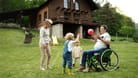 Mann im Rollstuhl spielt mit den Kindern Ball