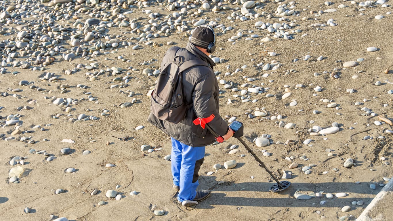 Ein Mann sucht nach Metall am Strand (Symbolfoto): Das sogenannte "Metal Detecting" hat sich zu einem Hobby für viele entwickelt.