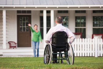 Mann im Rollstuhl vor seinem Haus