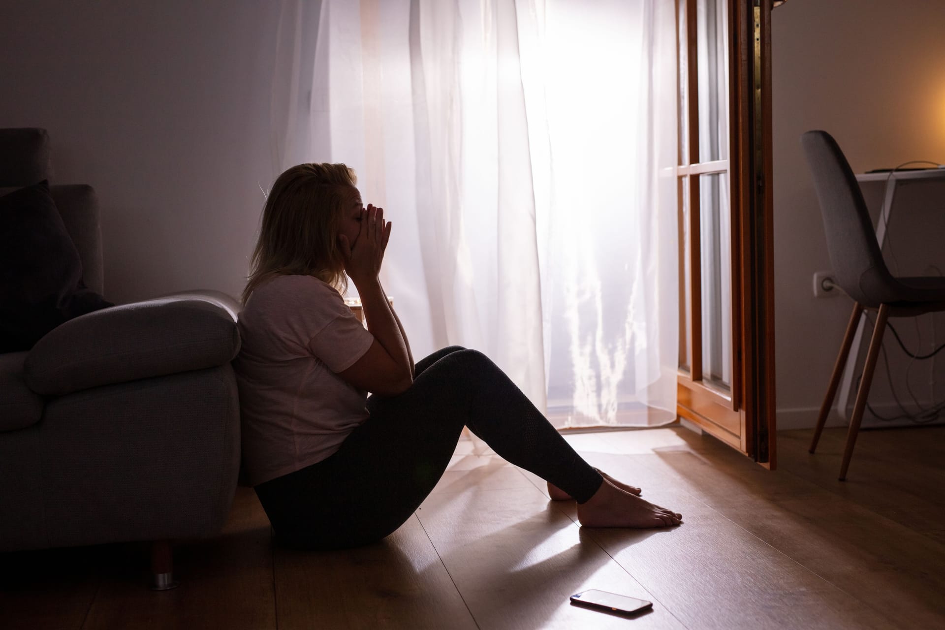 Eine Frau sitzt niedergeschlagen am Fenster