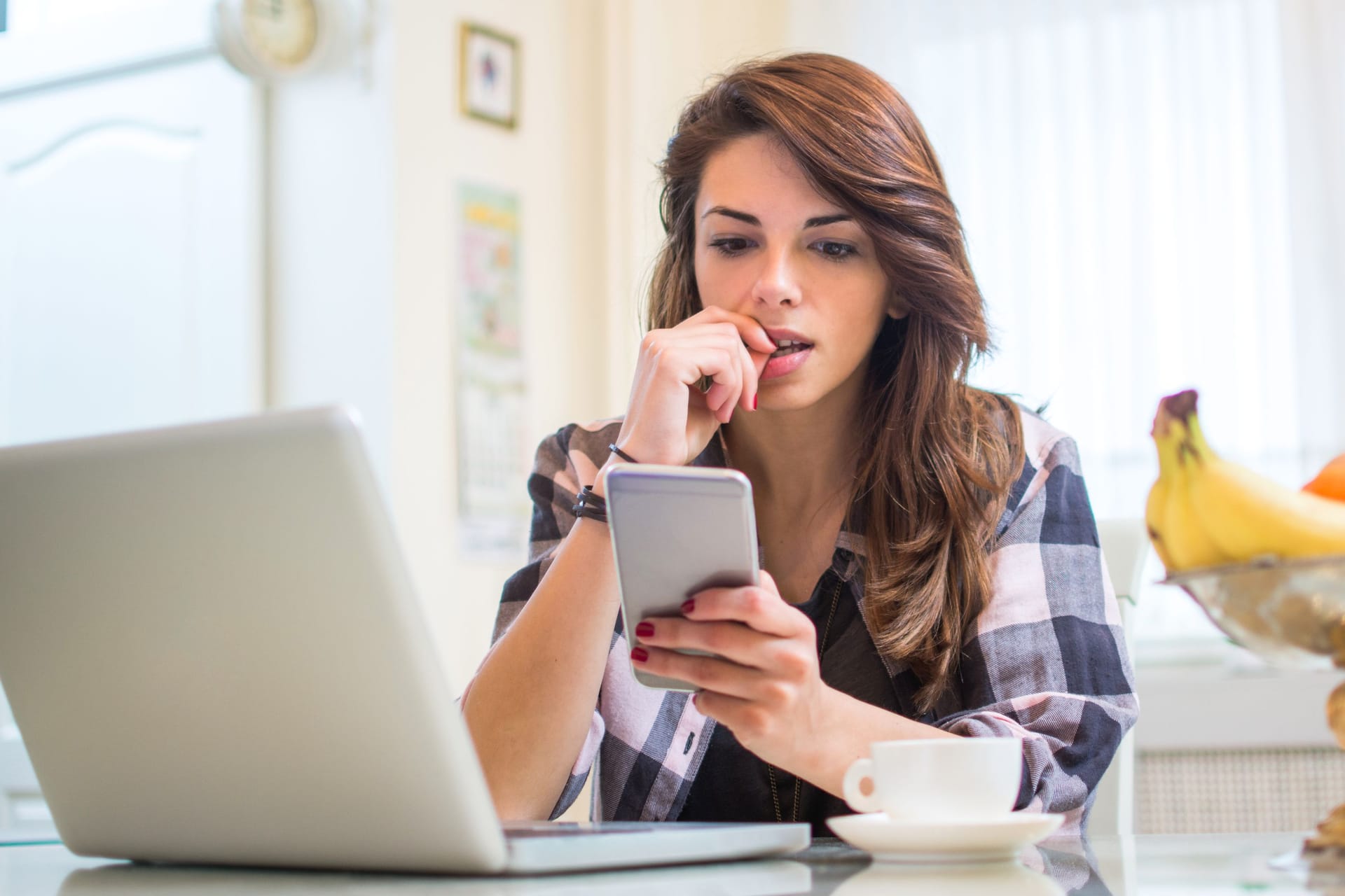 Eine Frau schaut auf ihr Smartphone: Die Angst, etwas zu verpassen (FOMO), kann denn Alltag stark beeinträchtigen.