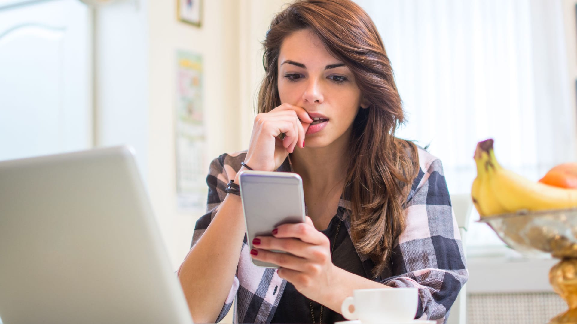 Eine Frau schaut auf ihr Smartphone: Die Angst, etwas zu verpassen (FOMO), kann denn Alltag stark beeinträchtigen.