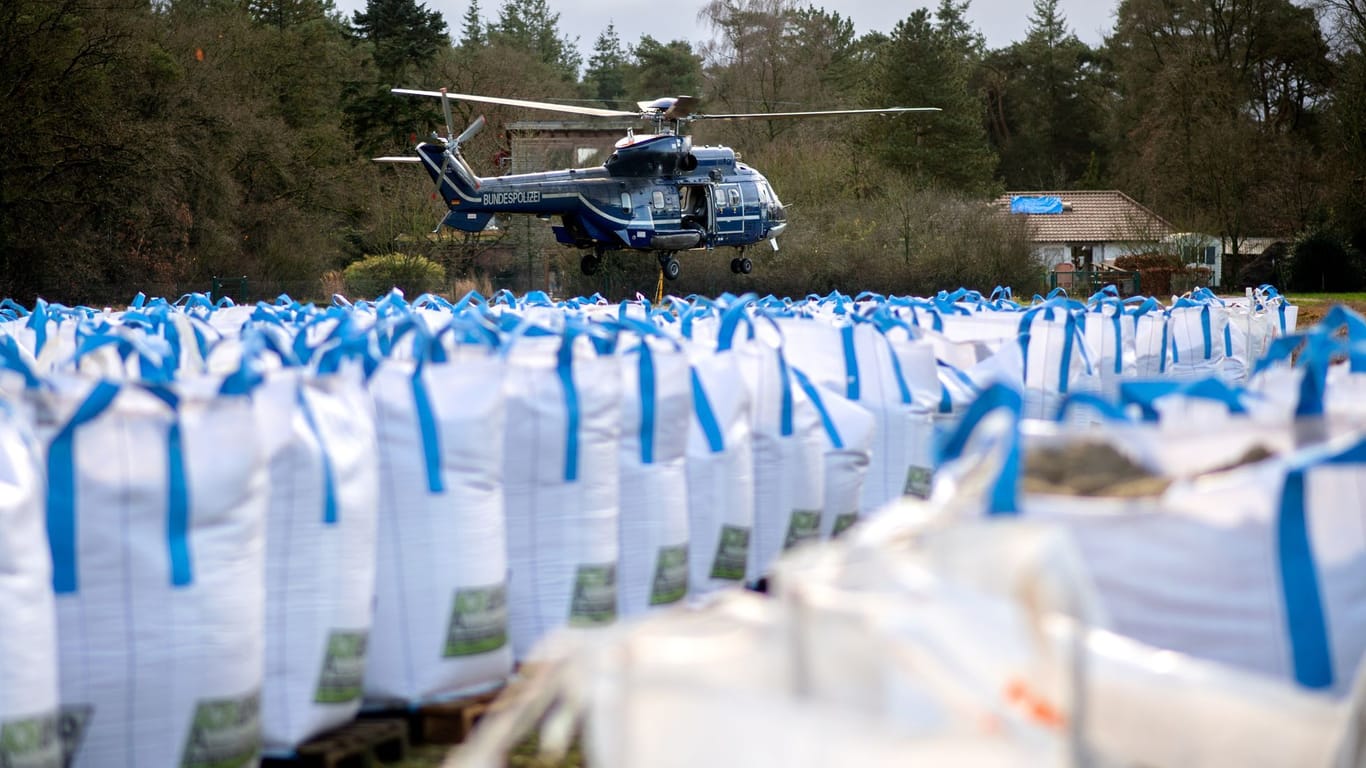 Ein Hubschrauber der Bundespolizei ist im Einsatz, um einen Deich mit großen Sandsäcken zu sichern. Das Waldgebiet nahe der Hunte ist vom Hochwasser stark betroffen.