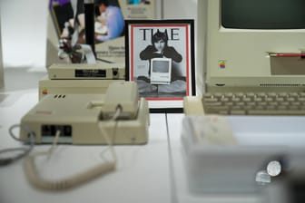 Bild von Steve Jobs mit alter Apple Technik und einem Apple Macintosh.