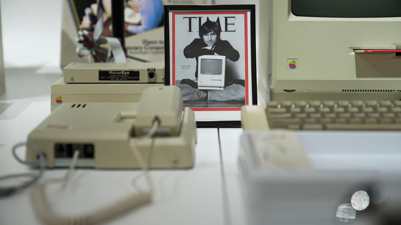 Bild von Steve Jobs mit alter Apple Technik und einem Apple Macintosh.