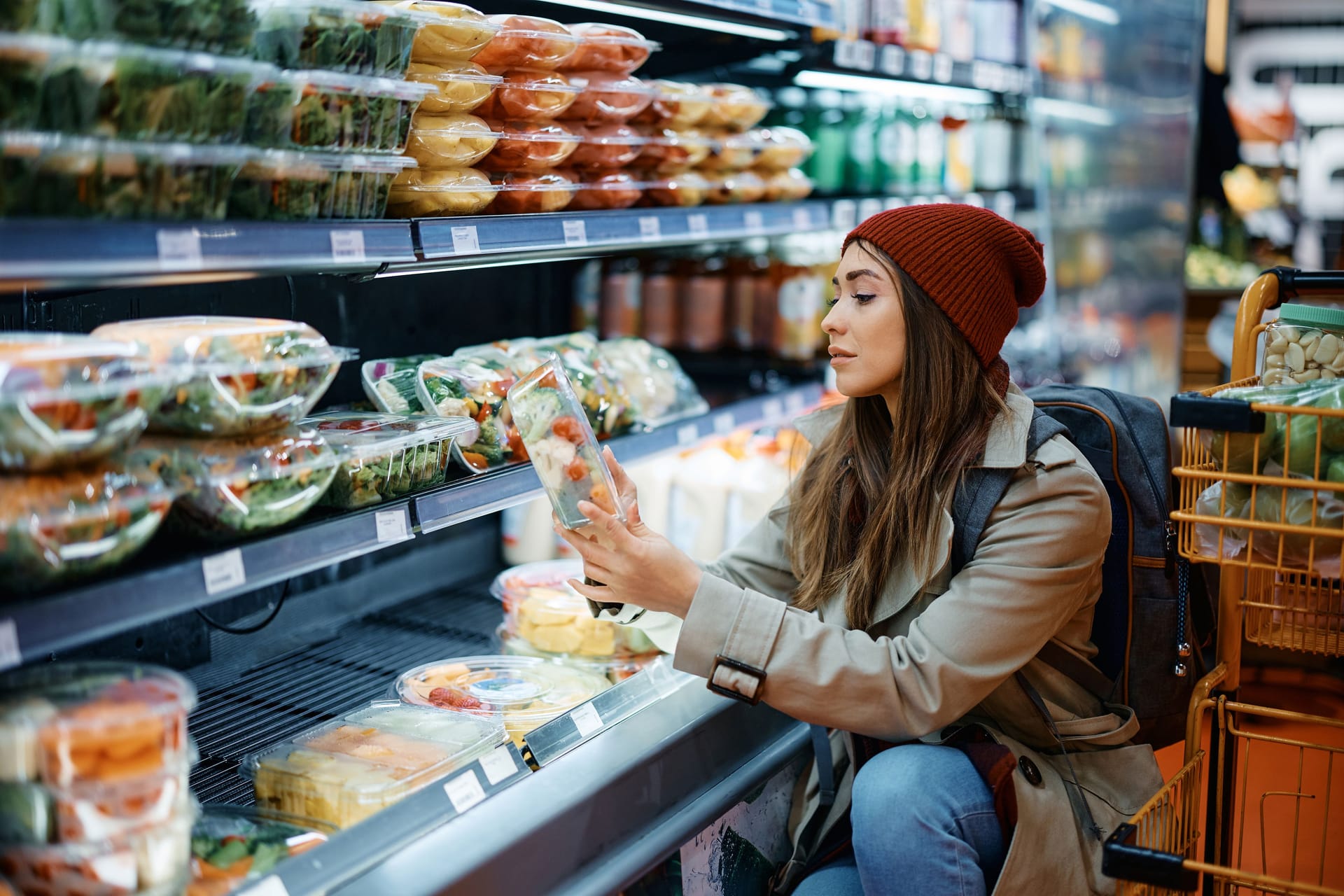 Eine Frau betrachtet eine Packung mit Fertigsalat: Vorgeschnitten, vorgewaschen und abgepackt: Fertigsalate sind schnell verfügbar und wirken gesund. Oft sind sie jedoch keimbelastet.