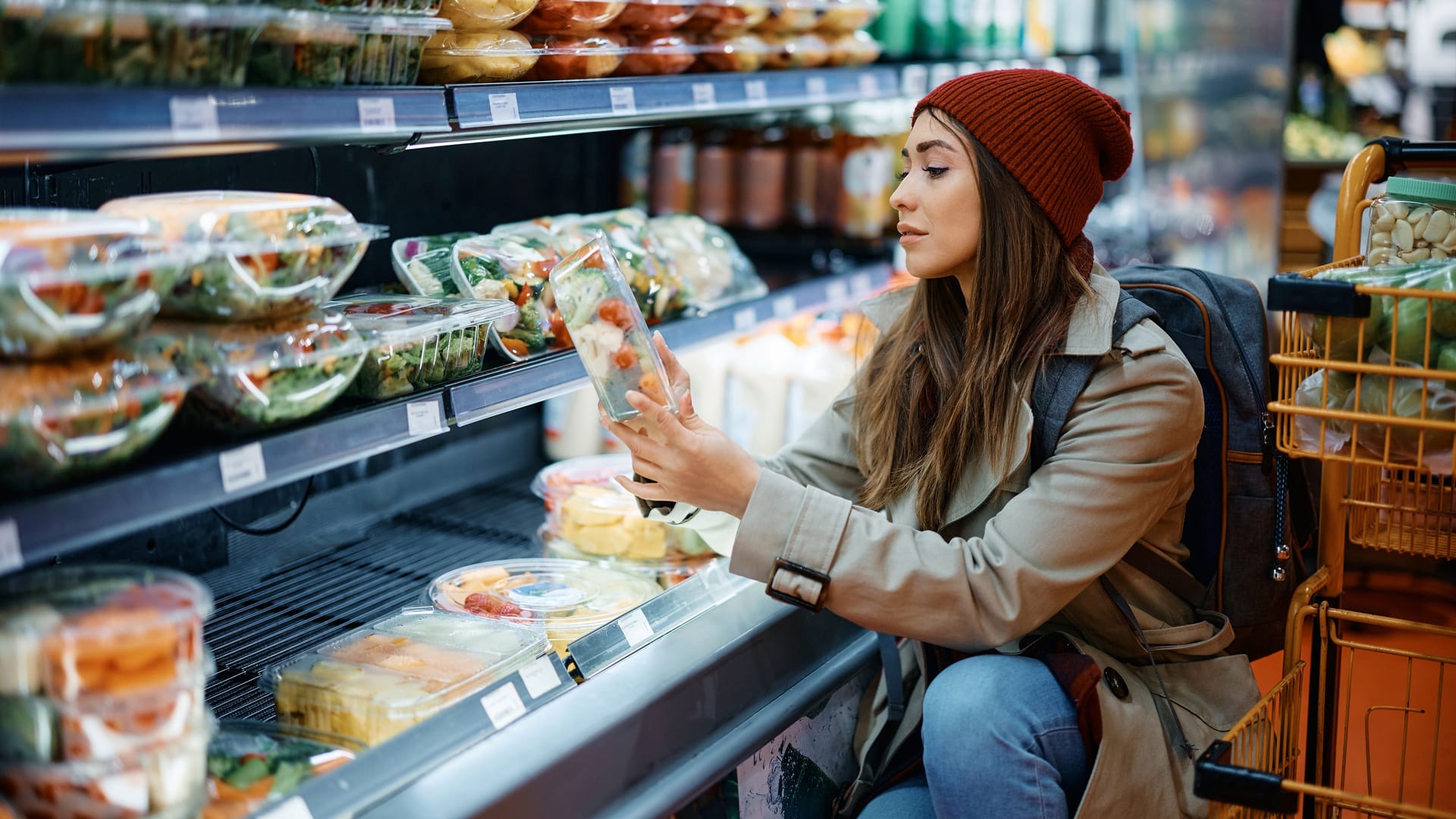 Eine Frau betrachtet eine Packung mit Fertigsalat: Vorgeschnitten, vorgewaschen und abgepackt: Fertigsalate sind schnell verfügbar und wirken gesund. Oft sind sie jedoch keimbelastet.