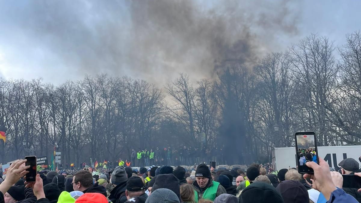 Bauerndemonstration: Aus der aufgebrachten Menge steigt Rauch auf.