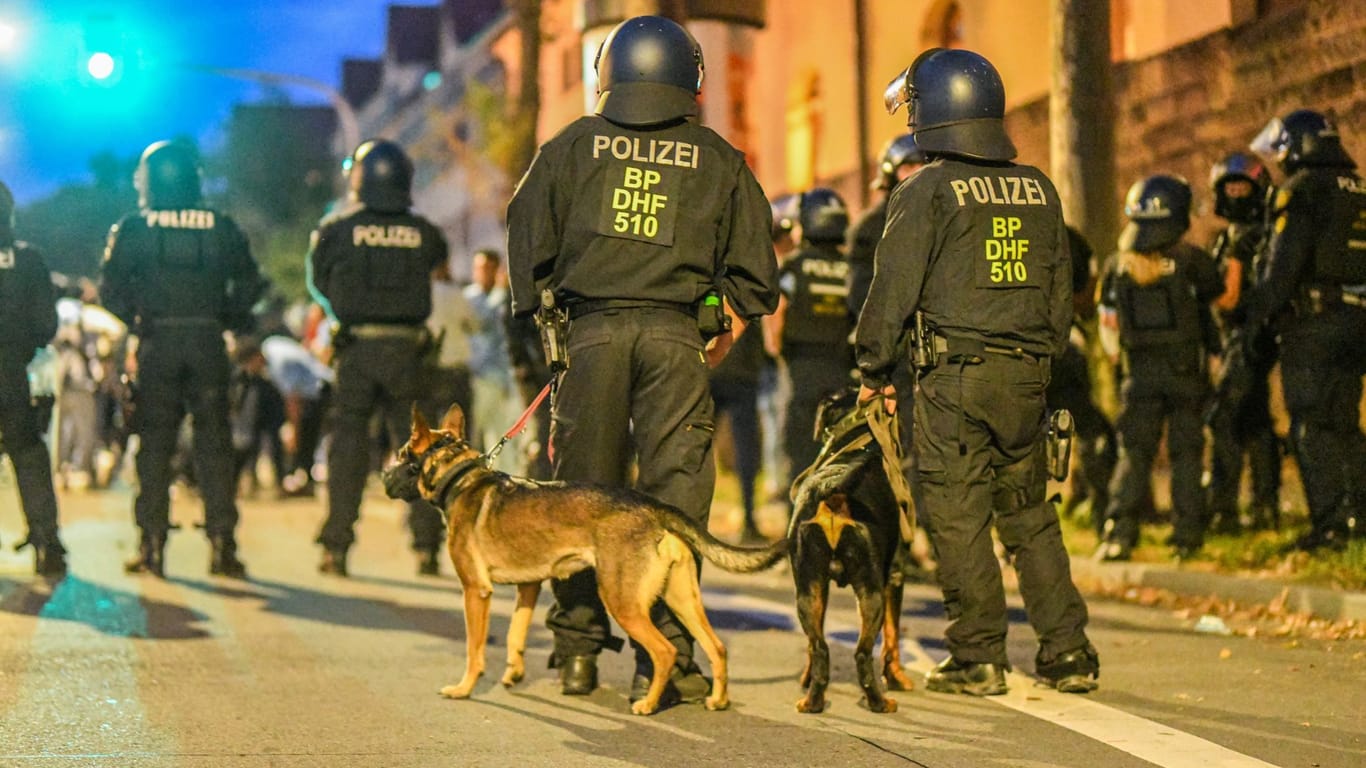 Einsatzkräfte der Polizei stehen mit Hunden nach Ausschreitungen bei einer Eritrea-Veranstaltung in Stuttgart auf der Straße (Archivfoto).