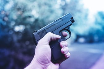 Männerhand mit Waffe (Symbolfoto): Bei einem Überfall auf einen Supermarkt war auch ein Kleinkind in Gefahr.