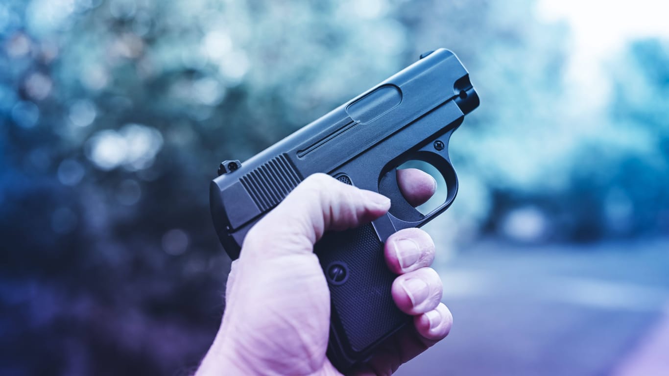 Männerhand mit Waffe (Symbolfoto): Bei einem Überfall auf einen Supermarkt war auch ein Kleinkind in Gefahr.