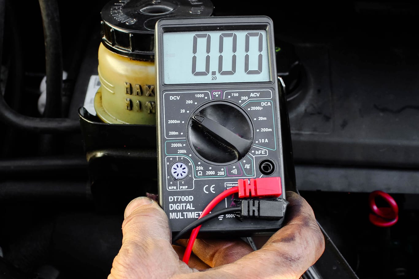 Checking voltage with multimeter. Recovery of acid batteries, resuscitate car battery. Voltmeter to check voltage level on car battery. Car service station. Car repair