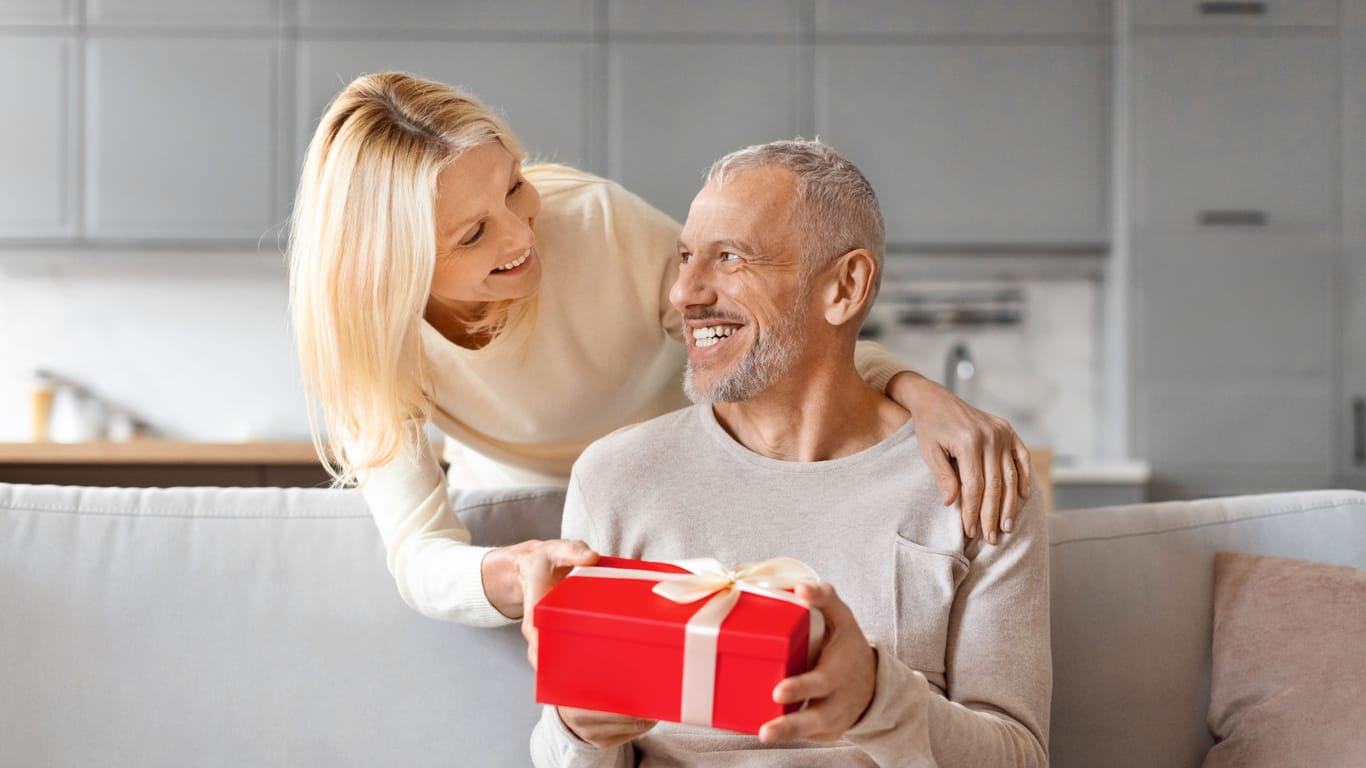 Loving mature woman giving present her surprised husband