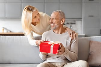 Loving mature woman giving present her surprised husband