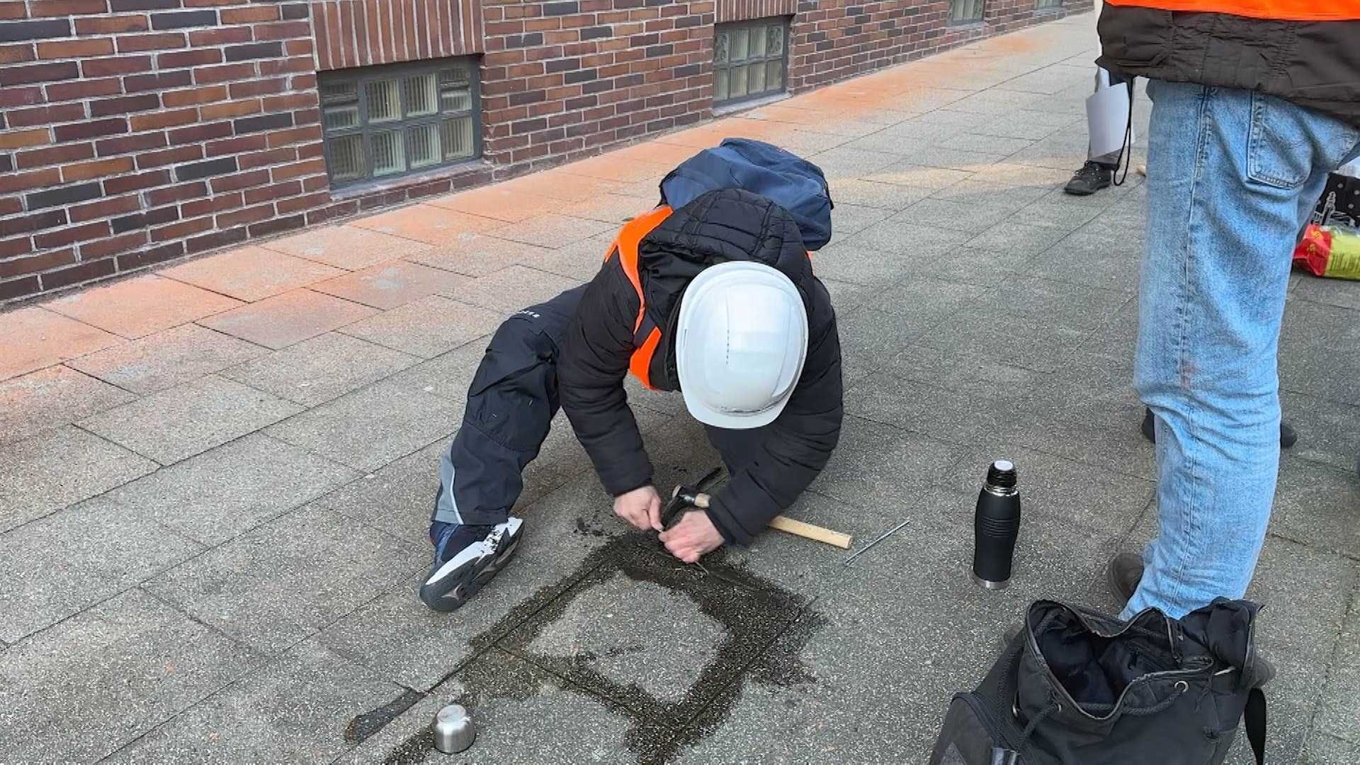 In Erinnerung an Lützerath: Eine Gruppe von Aktivisten traf sich am Donnerstagmorgen vor der Konzernzentrale von RWE, um dort Gehwegplatten mit Spitzhaken aufzuhebeln.