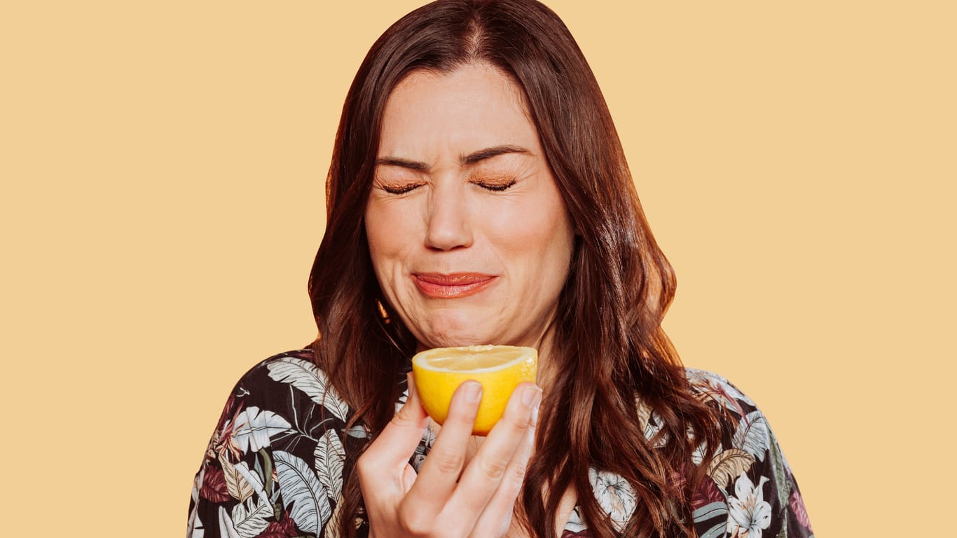 Eine Frau hat in eine Zitrone gebissen: Luft anhalten, in eine Zitrone beißen ... Dass Schluckauf äußerst störend sein kann, zeigt sich auch an den zahllosen Hausmitteln und Tipps, die als Gegenmaßnahmen kursieren.