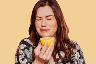 Eine Frau hat in eine Zitrone gebissen: Luft anhalten, in eine Zitrone beißen ... Dass Schluckauf äußerst störend sein kann, zeigt sich auch an den zahllosen Hausmitteln und Tipps, die als Gegenmaßnahmen kursieren.